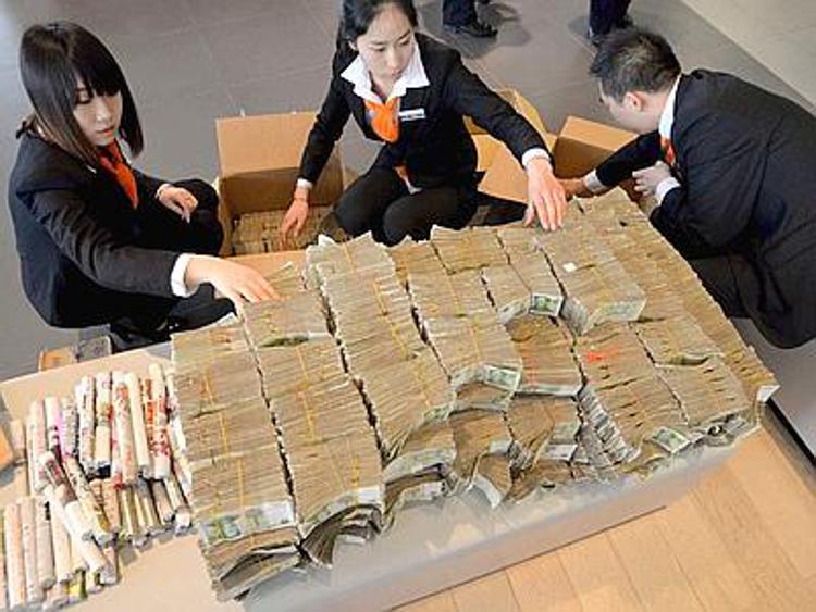 Cina, paga auto in contanti: commessi costretti a contare banconote /FOTO