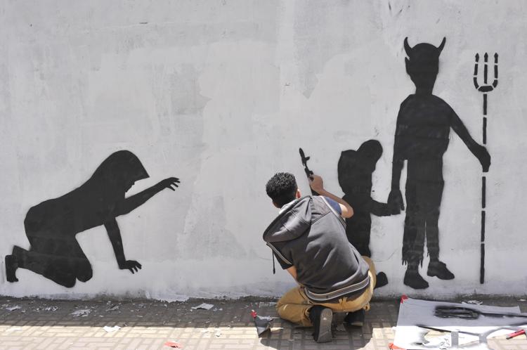 Sanaa, attivista realizza graffito contro il reclutamento di bambini soldato (foto Xinhua)
