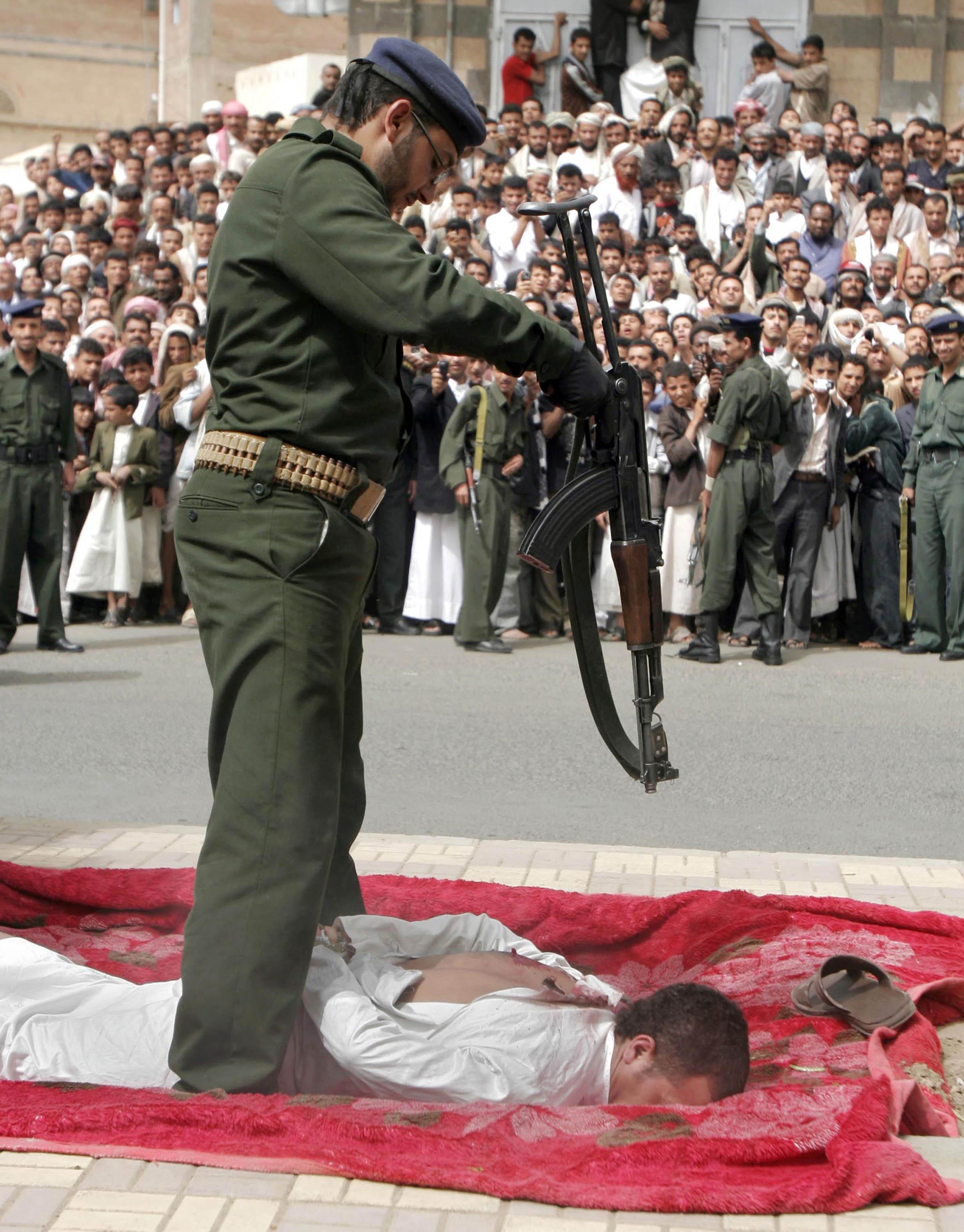 Yemenis gather to watch a Yemeni soldier stand over a man, lying face down on a large piece of red cloth, his hands bound behind him, after shooting him four times, in front of the central prison in San'a, Yemen, Monday, July 6, 2009. The Yemen news agency reports that a barber has been publicly executed after he was found guilty of raping and killing an 11-year-old boy who came to his shop for a haircut. According to the news agency, Saba, the barber was arrested in December 2008 and confessed during a January trial to raping the boy inside his salon, killing him and cutting his body to pieces before dumping it outside San'a. (AP Photo)