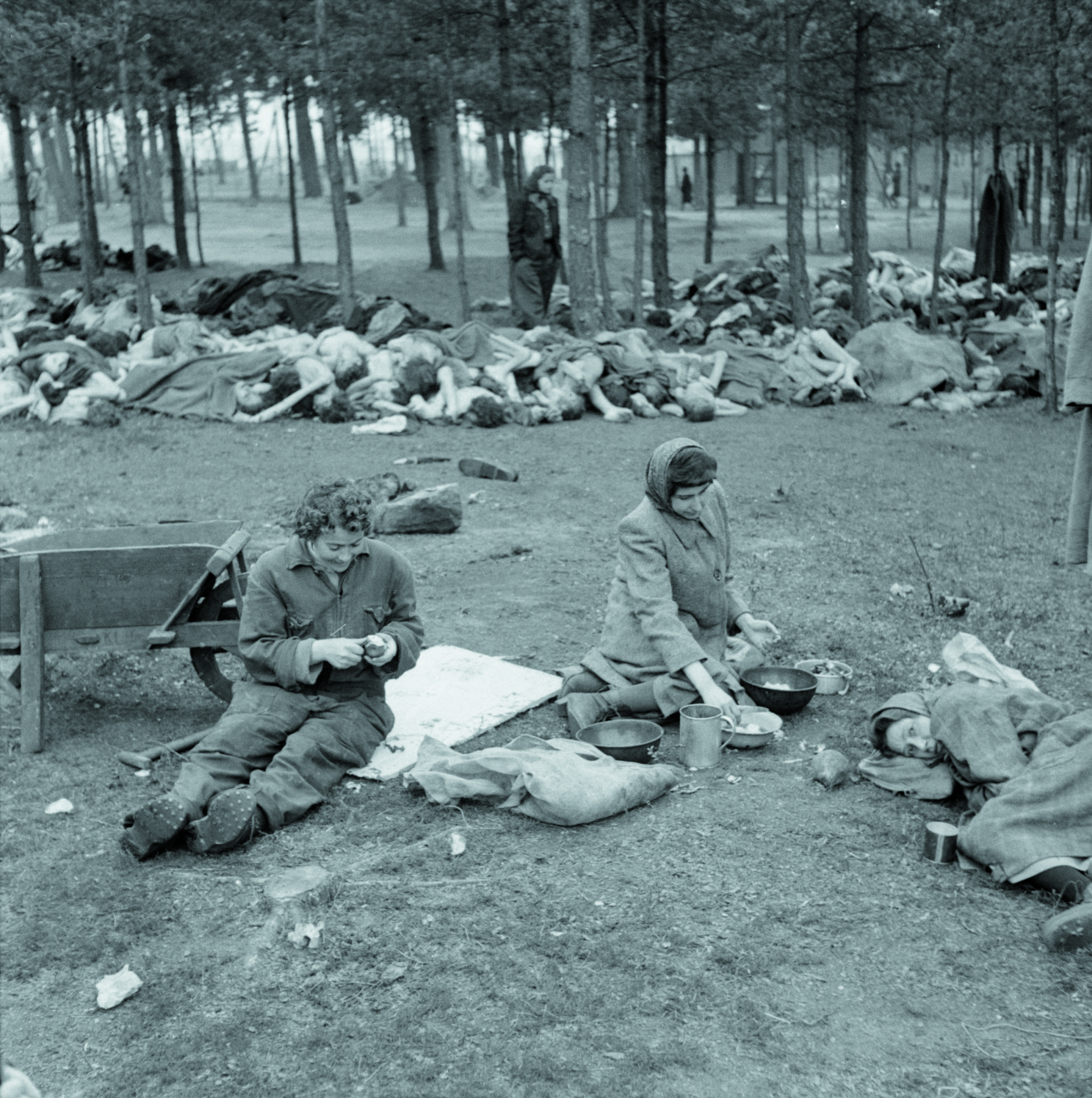 Bergen-Belsen, 18 aprile 1945: donne sopravvissute consumano un pasto improvvisato. Alle loro spalle cumuli di cadaveri