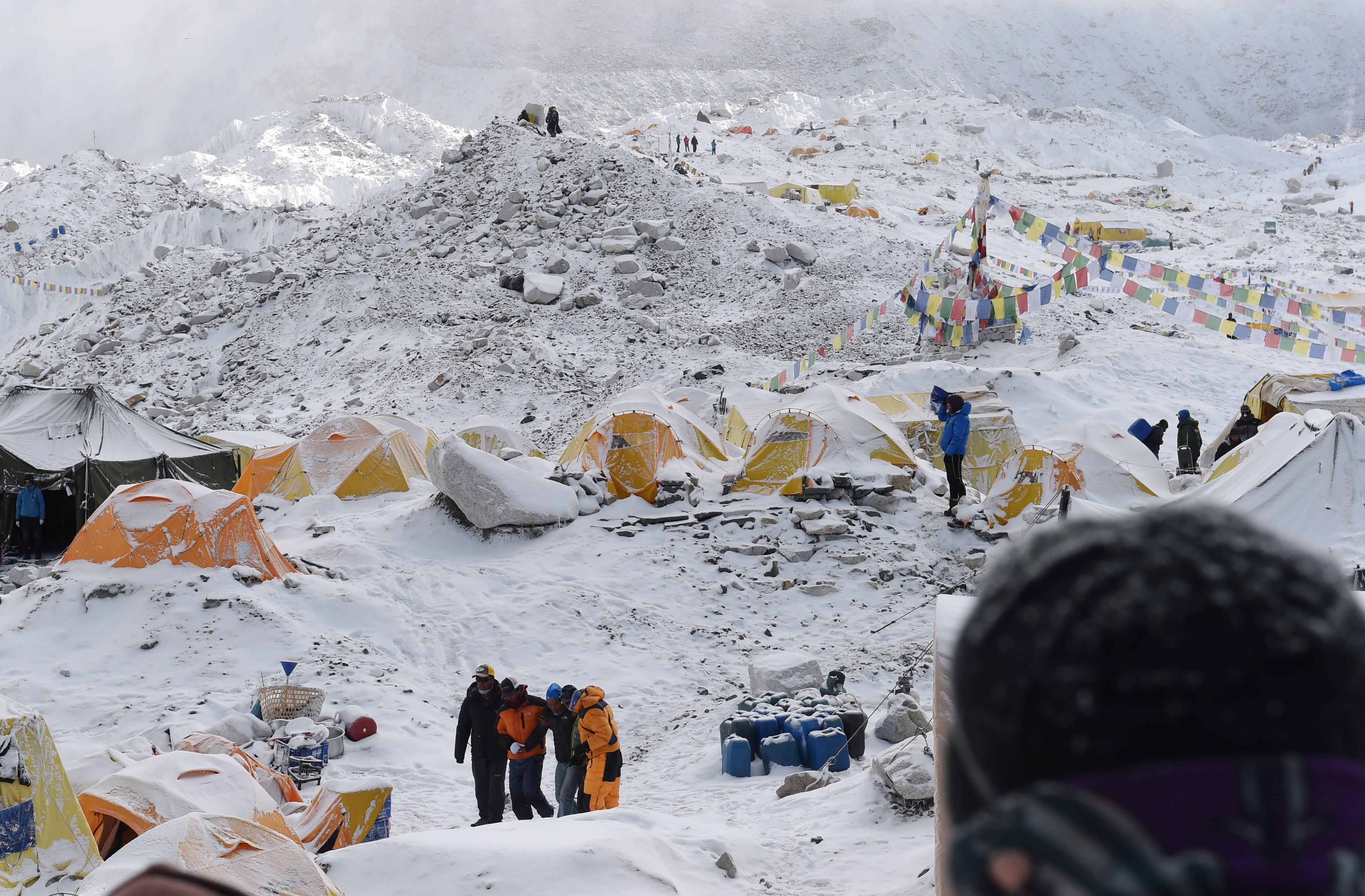 An injured person is helped to a landing area to be loaded onto a rescue helicopter at Everest Base Camp on April 26, 2015, a day after an avalanche triggered by an earthquake devastated the camp. Rescuers in Nepal are searching frantically for survivors of a huge quake on April 25, that killed nearly 2,000, digging through rubble in the devastated capital Kathmandu and airlifting victims of an avalanche at Everest base Camp. The bodies of those who perished lie under orange tents. AFP PHOTO/ROBERTO SCHMIDT