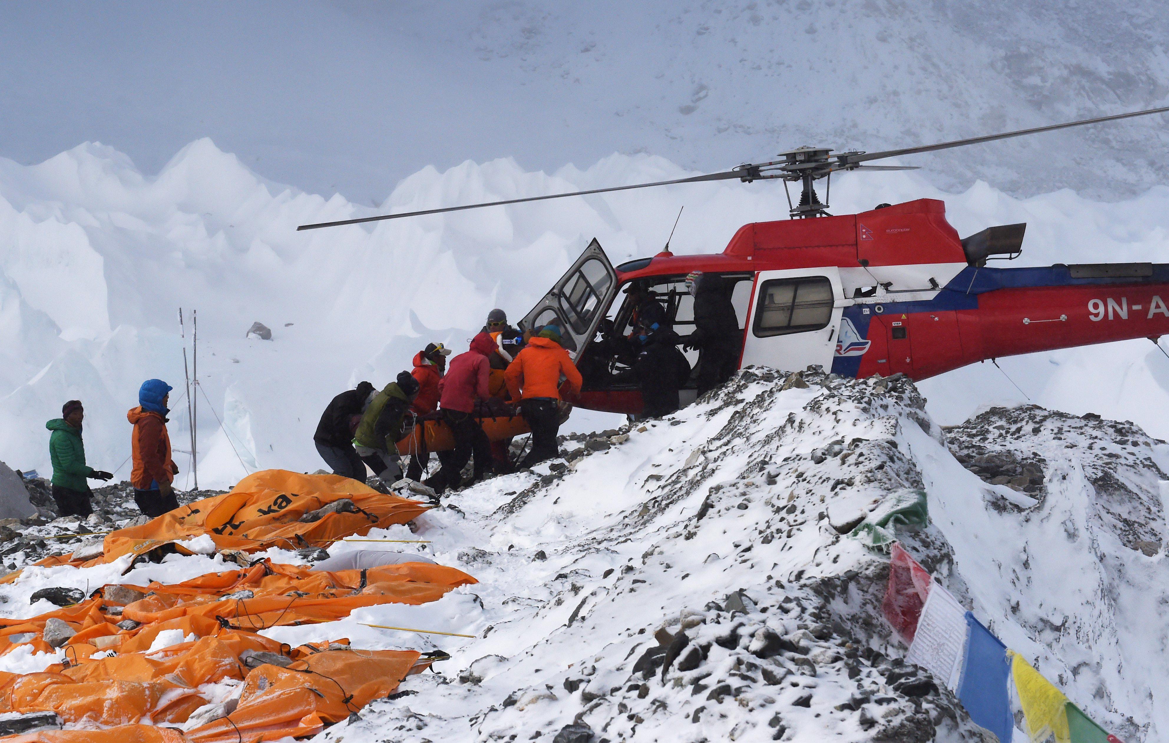 An injured person is loaded onto a rescue helicopter at Everest Base Camp on April 26, 2015, a day after an avalanche triggered by an earthquake devastated the camp. Rescuers in Nepal are searching frantically for survivors of a huge quake on April 25, that killed nearly 2,000, digging through rubble in the devastated capital Kathmandu and airlifting victims of an avalanche at Everest base Camp. The bodies of those who perished lie under orange tents. AFP PHOTO/ROBERTO SCHMIDT