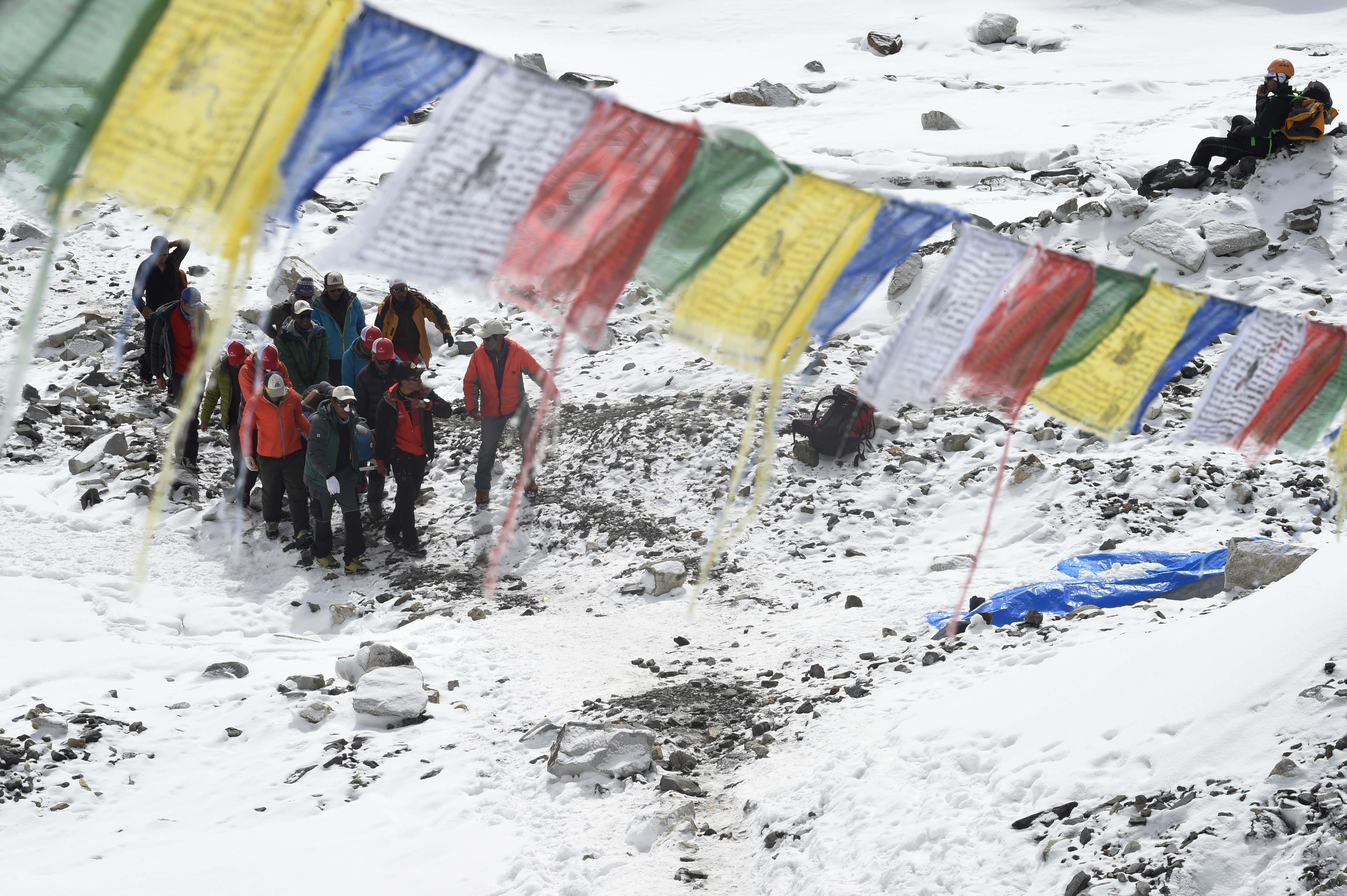 Rescue team personnel carry an injured person towards a waiting rescue helicopter at Everest Base Camp on April 26, 2015, a day after an avalanche triggered by an earthquake devastated the camp. Rescuers in Nepal are searching frantically for survivors of a huge quake on April 25, that killed nearly 2,000, digging through rubble in the devastated capital Kathmandu and airlifting victims of an avalanche at Everest base camp. AFP PHOTO/ROBERTO SCHMIDT