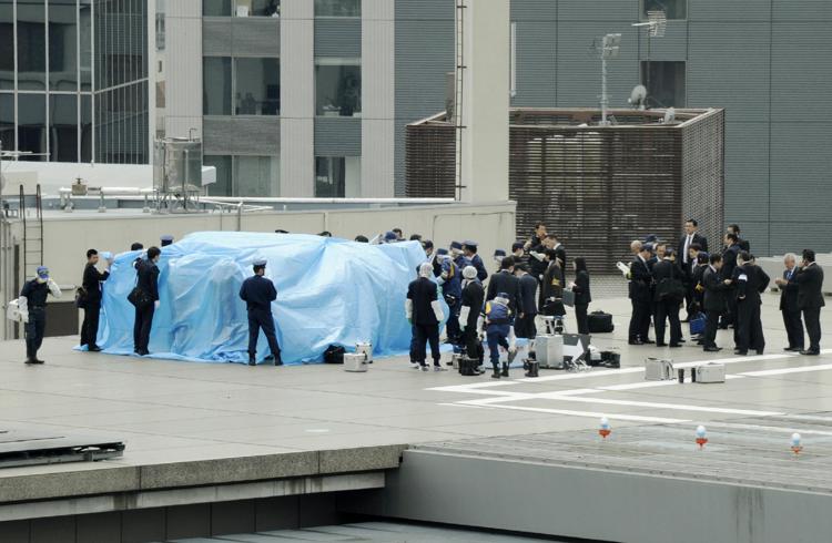 Agenti di polizia coprono il drone trovato sul tetto dell'ufficio del primo ministro del Giappone, Shinzo Abe, nel centro di Tokyo con un telo di plastica azzurro (Afp) - AFP
