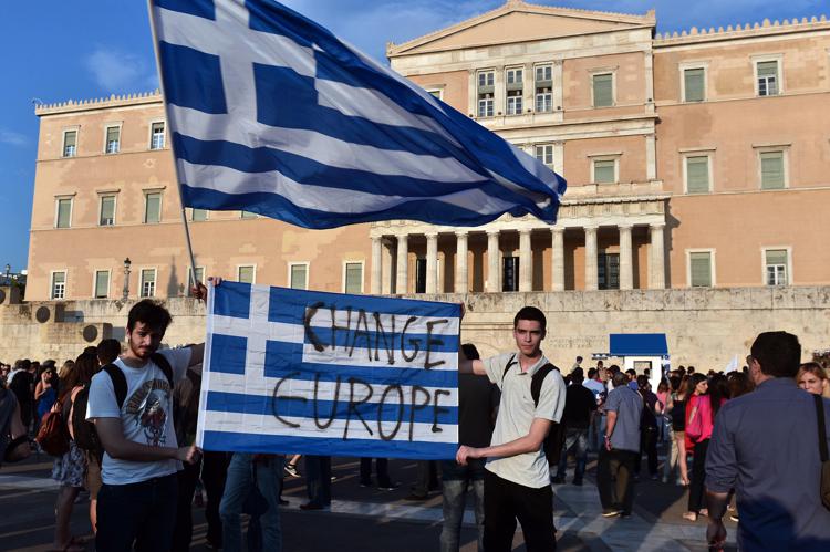 Protesters hold a greek flag with ' change Europe' slogan on it in front of the Greek parliament in Athens, on June 29, 2015. Some 17,000 people took to the streets of Athens and Thessalonique to say 'No' to the latest offer of a bailout deal, accusing Greece's international creditors of blackmail. AFP PHOTO / LOUISA GOULIAMAKI - AFP