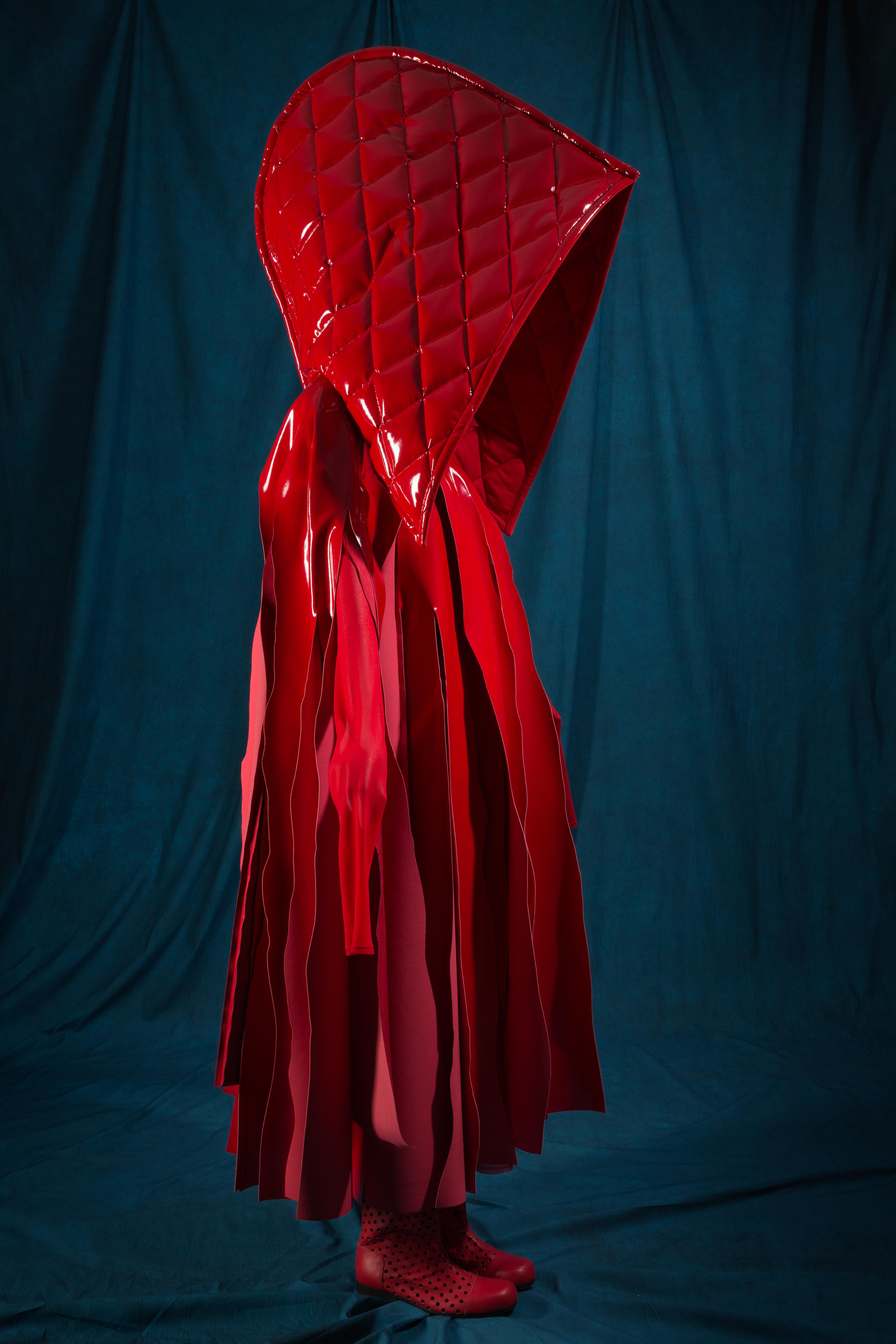 Una cappa rossa in vernice di Comme des Garçons per la primavera-estate 2015 che ricorda 'Cappuccetto Rosso'. Photograph © The Museum at FIT