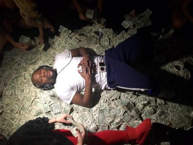 Floyd Mayweather su un letto di dollari (foto dal profilo twitter del pugile)