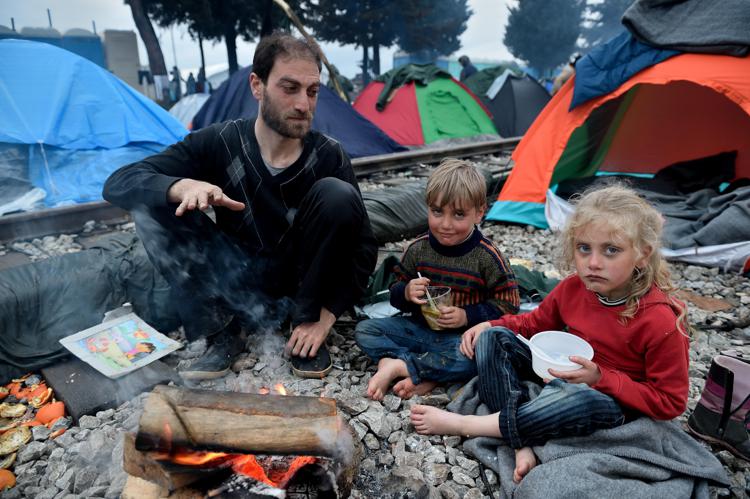 Un padre siriano  con i due figli a Idomeni, al confine fra Grecia e Macedonia (foto Afp) 