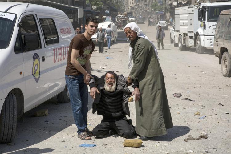 Un uomo in stato di choc riceve soccorsi in strada dopo un raid aereo (AFP PHOTO) - (AFP PHOTO)