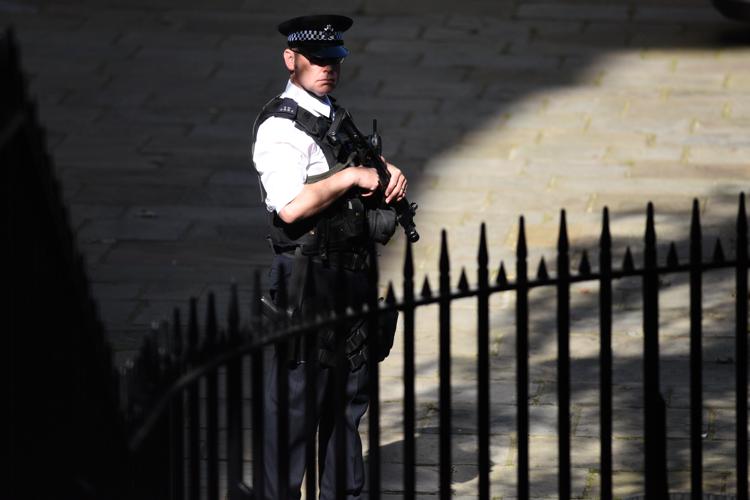 An armed police officer stands guard in Downing Street in London on July 15, 2016. / AFP PHOTO / OLI SCARFF - AFP