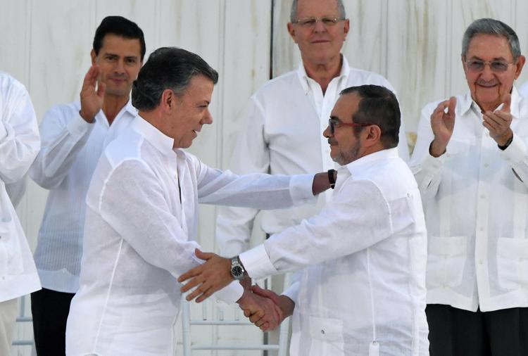 Il presidente colombiano Juan Manuel Santos e il leader delle Farc Timoleon Jimenez, detto Timochenko, si stringono la mano durante lo storico accordo di pace (Afp)