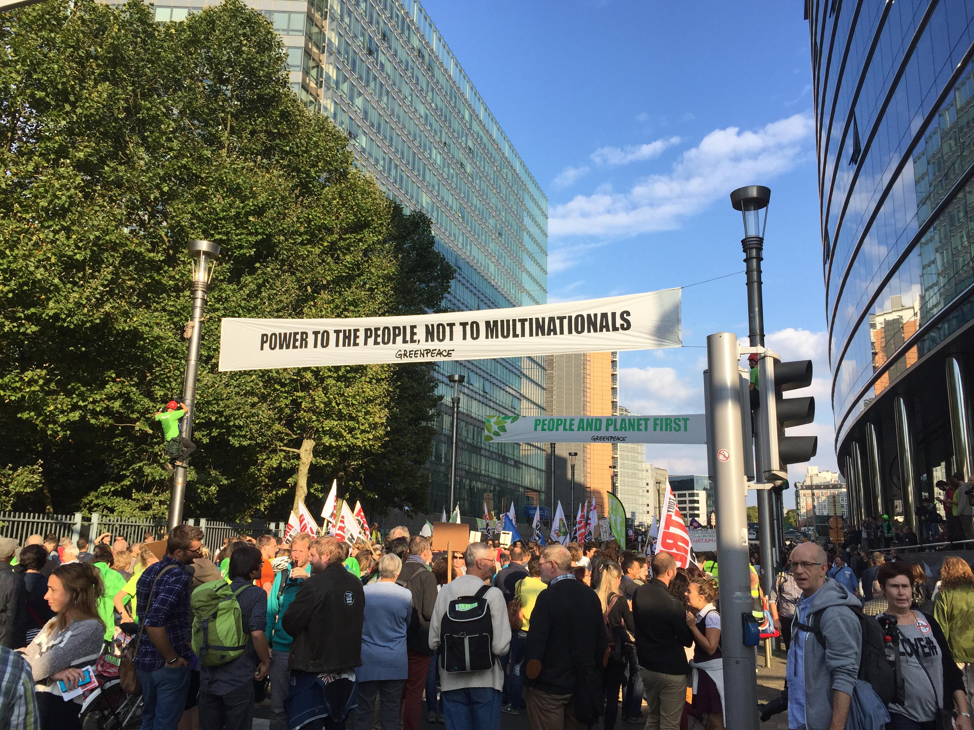 "Potere ai popoli, non alle multinazionali", proclama lo striscione di Greenpeace appeso davanti ai palazzi della Commissione e del Consiglio, a Bruxelles