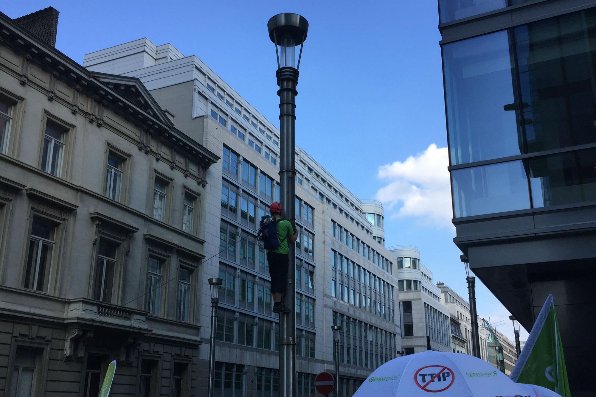 Un attivista di Greenpeace si arrampica su un lampione lungo rue de la Loi