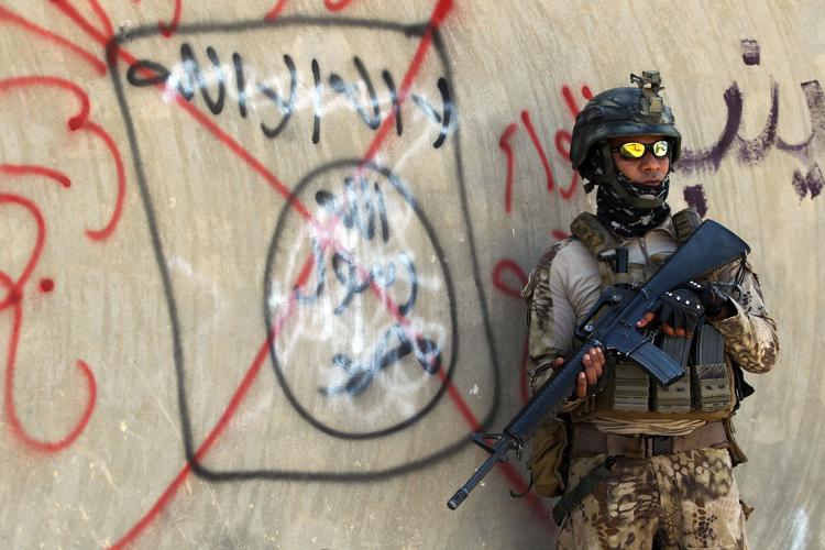 Un soldato iracheno vicino ad un simbolo dell'Is cancellato su un muro di Falluja (AFP PHOTO) - (AFP PHOTO)