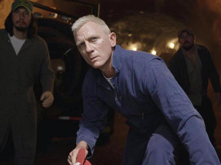 Daniel Craig in primo piano in una scena di 'Logan Lucy', dietro di lui, in penombra, a sinistra Adam Driver e a destra Channing Tatum  