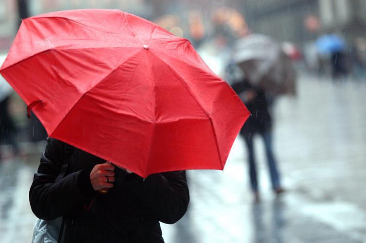 Persona si ripara dalla pioggia sotto l'ombrello - (Fotogramma)
