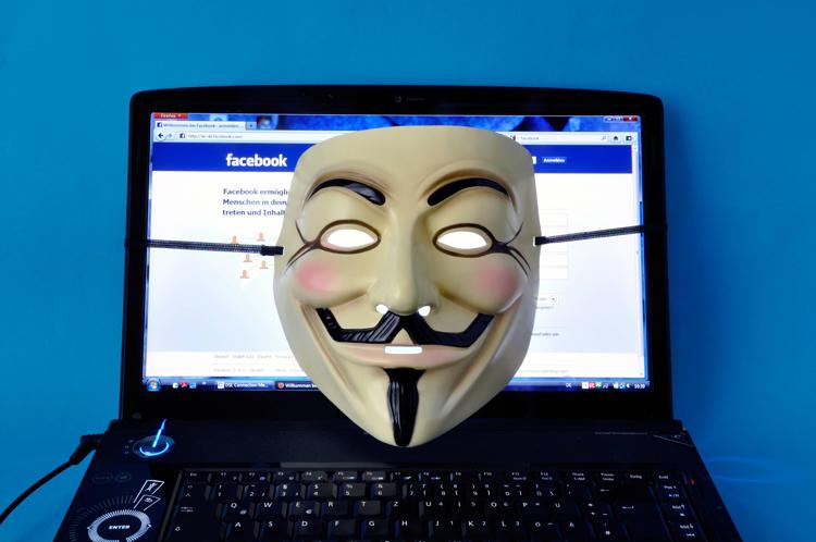Anonymous' signature Guy Fawkes  mask is pictured lying on a laptop, which displays the Facebook Internet page - INFOPHOTO
