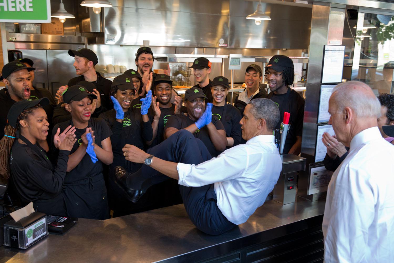 Obama catturato dall'obiettivo mentre salta a sedere sul bancone dello Shake Shack restaurant di Washington per farsi una foto con lo staff il 16 maggio 2014.
