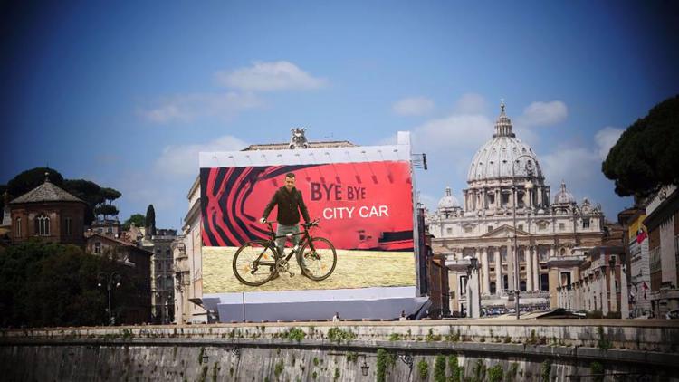Roma: ciclisti romani ironizzano sul maxicartellone in Vaticano