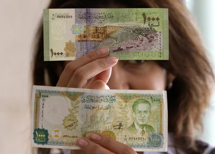 Sopra la nuova banconota da mille lire siriane. Sotto la 'vecchia' versione, con l'immagine dell'ex presidente Hafez al-Assad al posto di un anfiteatro romano. AFP PHOTO/ LOUAI BESHARA - AFP