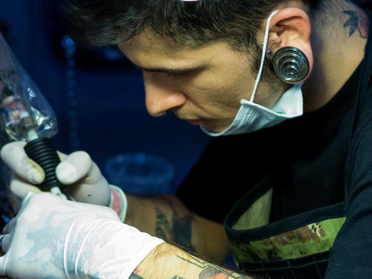 Tatuatore al lavoro (Infophoto)