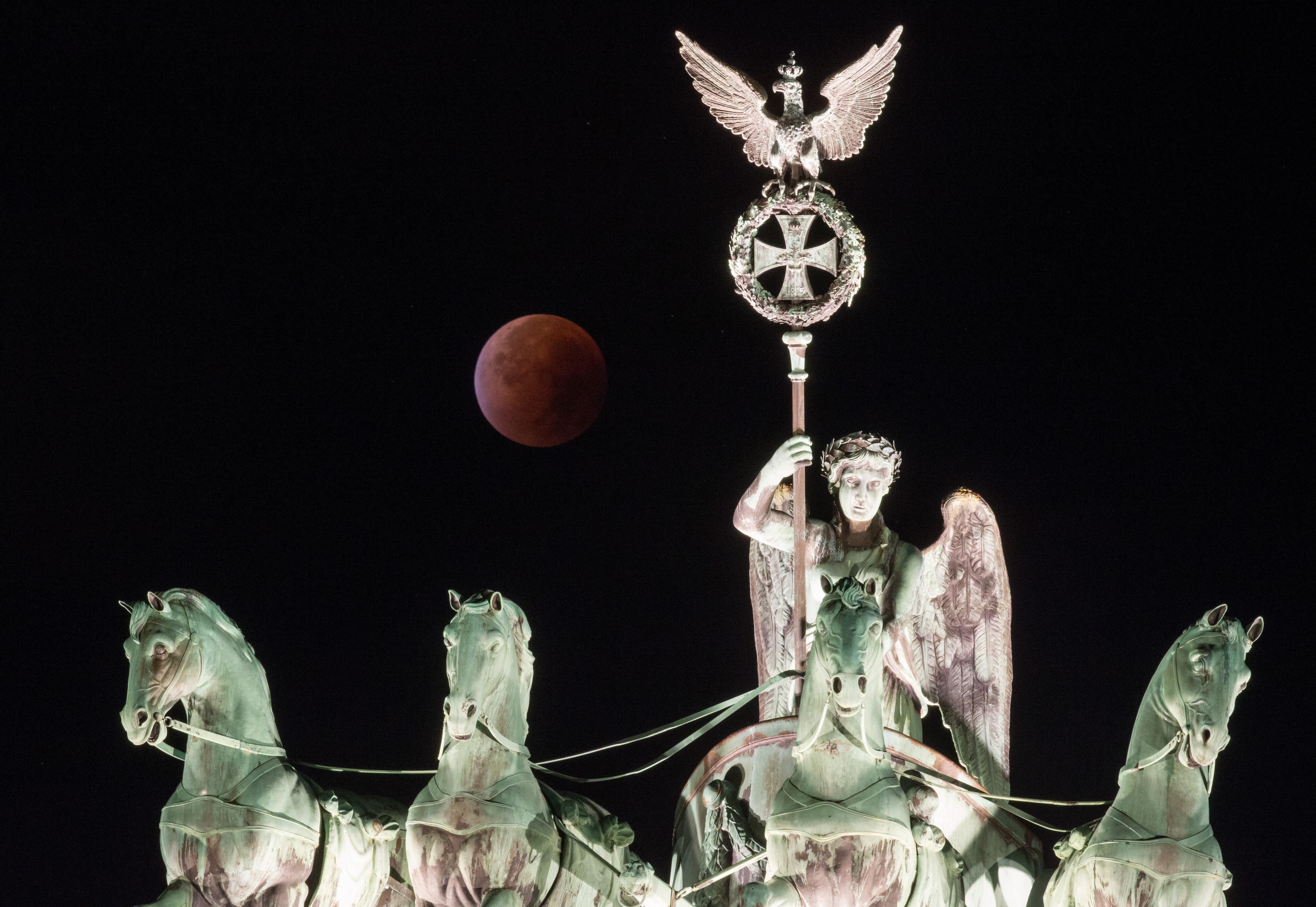 La "luna di sangue" dietro la scultura Quadriga in cima al simbolo di Berlino alla Porta di Brandeburgo (AFP PHOTO / DPA / KAY NIETFELD)