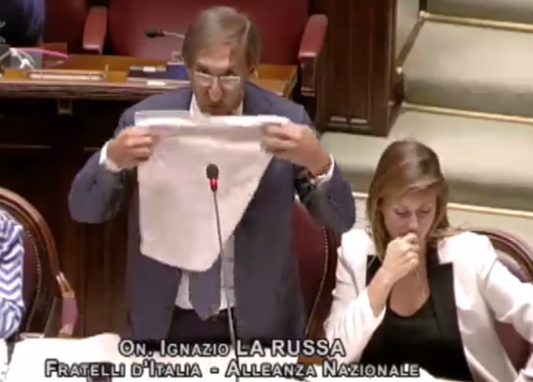 Ignazio La Russa mentre afferra il tovagliolo per imbavagliarsi (Fermo immagine dal video pubblicato sul canale Youtube di Giorgia Meloni)
