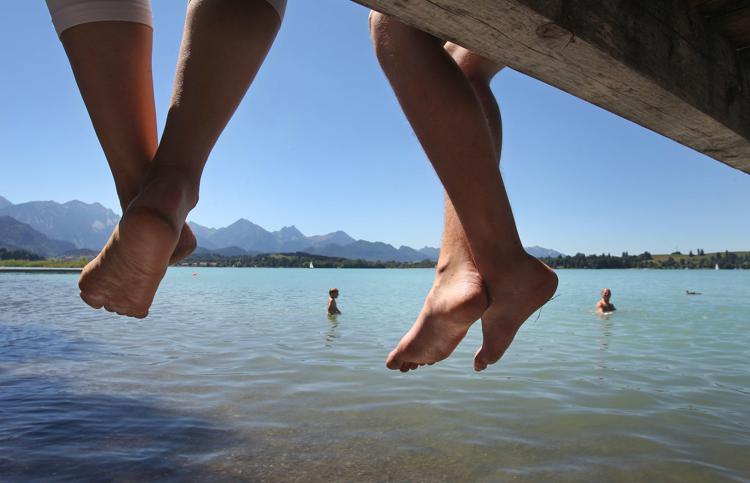 People sit on a pier while others swim in Lake Forggen near Waltenhofen, Germany, 01 August 2013. Photo: KARL-JOSEFHILDENBRAND - Infophoto - INFOPHOTO