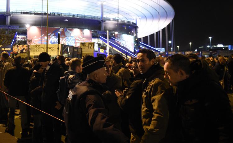Football fans talk to a policeman securing an area outside the Stade de France stadium following the friendly football match between France and Germany in Saint-Denis, north of Paris, on November 13, 2015, after a series of gun attacks occurred across Paris as well as explosions outside the national stadium where France was hosting Germany. At least 18 people were killed, with at least 15 people killed at the Bataclan concert hall in central Paris, only around 200 metres from the former offices of Charlie Hebdo which were attacked by jihadists in January. AFP PHOTO / FRANCK FIFE - AFP