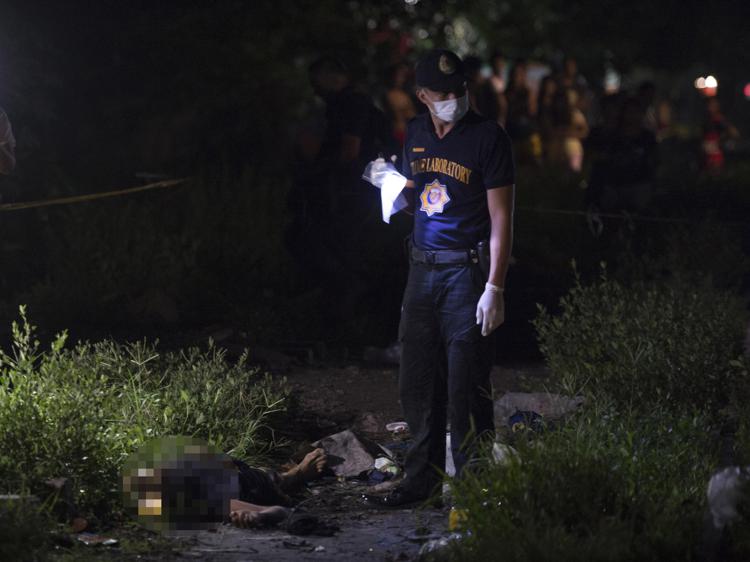 Members of police Scene of the Crime Operative (SOCO) look for evidence at the scene next to a dead suspected drug pusher killed during a drug buy-bust operation by police along a rail line in Caloocan City suburban Manila on early September 30, 2016. Philippine President Rodrigo Duterte on September 30 drew a parallel with his deadly crime war and Hitler's massacre of Jews, as he said he was 