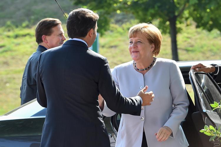 Italian Prime Minister Matteo Renzi (L) welcomes German Chancellor Angela Merkel (R), as she arrives at the Ferrari Track in Maranello on August 31, 2016. / AFP PHOTO / GIUSEPPE CACACE - AFP