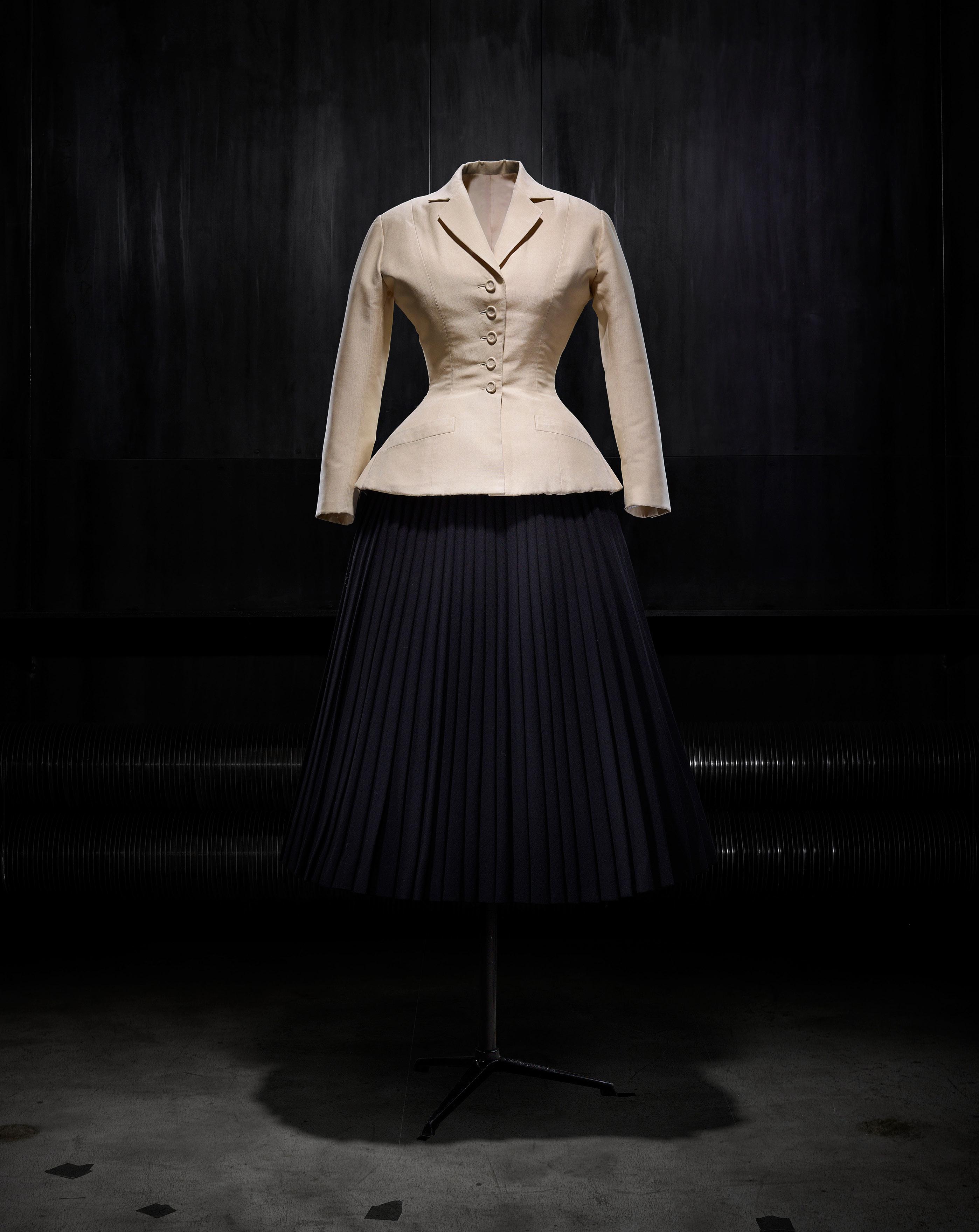 Il tailleur Bar realizzato nel 1947 da Christian Dior e composto da una giacca in shantung naturale e da una gonna a corolla plissettata di lana nera, collezione di haute couture printemps-été 1947, linea Corolle.