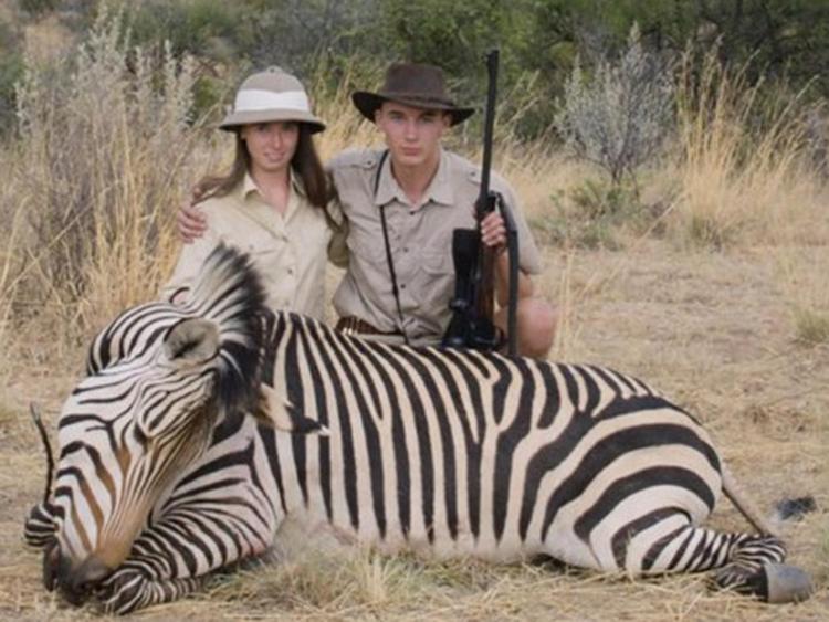 Una delle coppie di turisti - caciatori raccontate da 'Safari' posa con il cadavere di una giraffa che ha appena abbattuto 