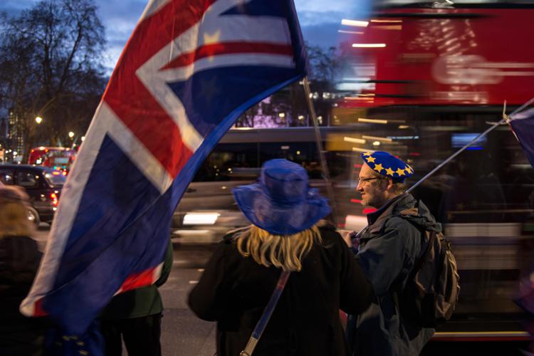 Anti-Brexit supporters hold flags as they demonstrate outside the Houses of Parliament on January 14, 2019. - Prime Minister Theresa May on Monday published further assurances from the EU on the eve of a crucial parliamentary vote on her Brexit deal and warned MPs that rejecting it would lead to 
