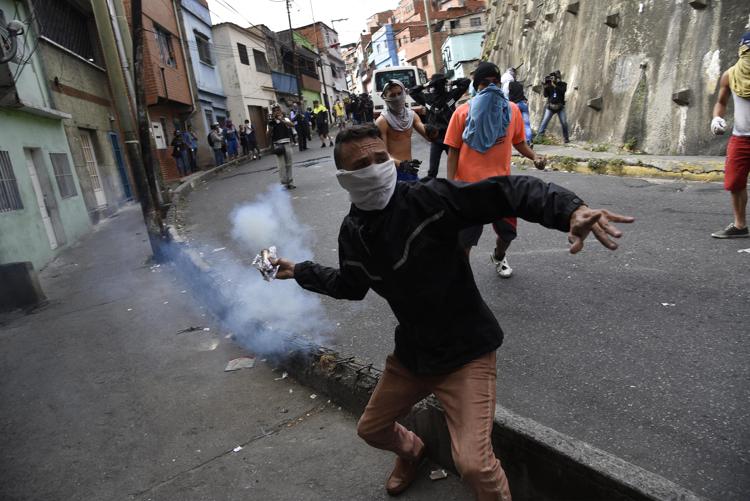 A demonstrator throws back a tear gas canister during a protest in the Cotiza neighborhood of Caracas, Venezuela, on Jan. 21, 2019.  Bloomberg photo by Carlos Becerra.