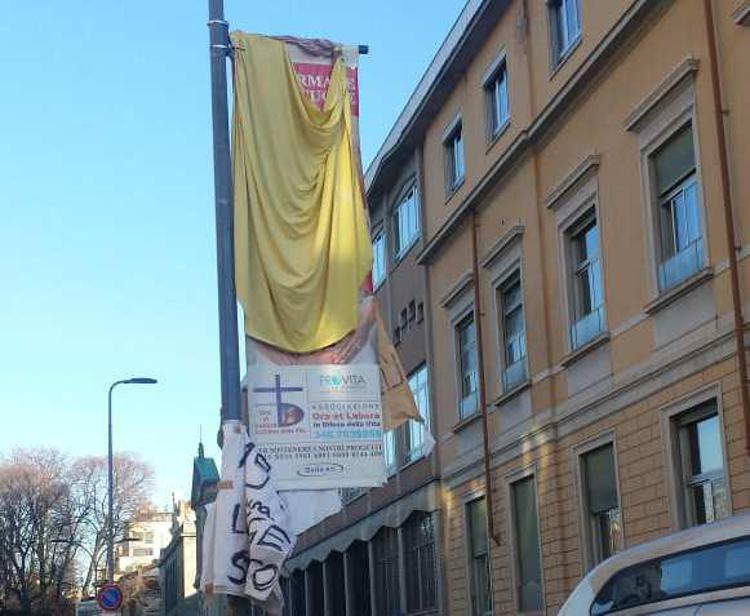 Il manifesto anti-aborto coperto da lenzuola davanti all'ingresso della clinica Mangiagalli di Milano