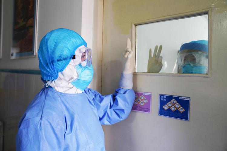 This photo taken on January 28, 2020 shows medical staff members gesturing to each other in an isolation ward at a hospital in Zouping in China's easter Shandong province. - China faced deepening isolation over its coronavirus epidemic on February 1 as the death toll soared to 259, with the United States leading a growing list of nations to impose extraordinary Chinese travel bans. (Photo by STR / AFP) / China OUT