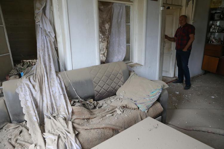 Un civile e la sua casa distrutta negli scontri tra le due ex Repubbliche sovietiche (Afp)