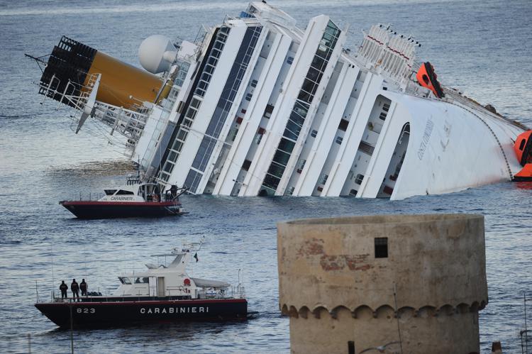 (FILES) This file photo taken on January 18, 2012 shows the cruise liner Costa Concordia aground in front of the harbour of the Isola del Giglio (Giglio island) after hitting underwater rocks on January 13. The fate of Francesco Schettino, the captain of the doomed Costa Concordia cruise liner hung in the balance on May 12, 2017 as his defence lawyers prepared to sum up and Italy's highest court readied its ruling. Schettino, dubbed 