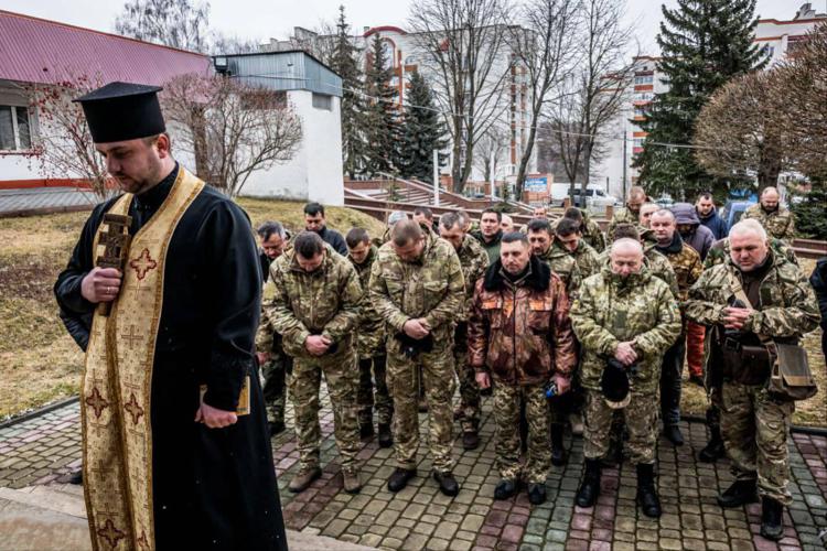 Un prete benedice alcuni soldati ucraini sul fronte Ovest (foto di Carlo Cozzoli/Fotogramma)