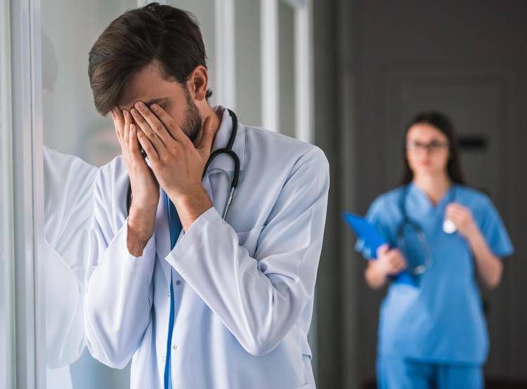 Medico con viso tra le mani -