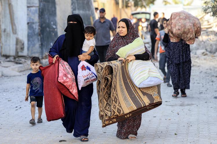 Donne palestinesi camminano con bambini e oggetti personali nel sud della Striscia di Gaza - (Afp)