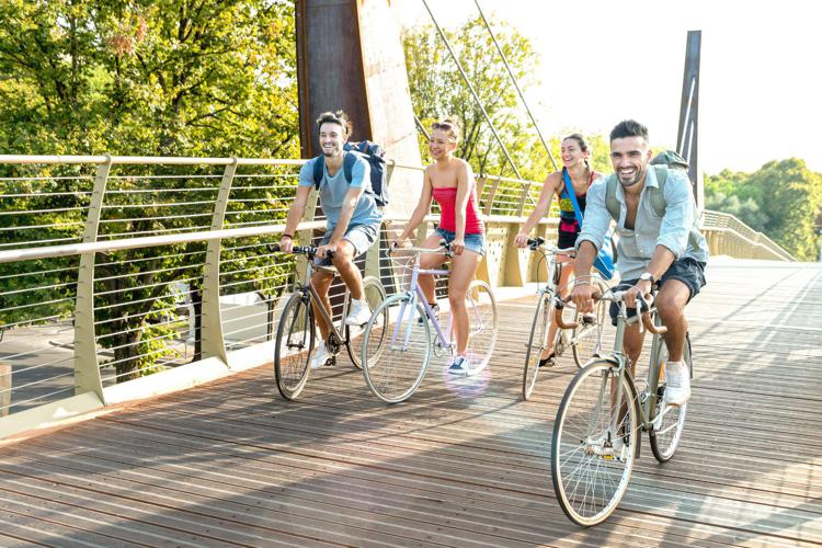 Ragazzi che vanno in bici su ponte - Canva