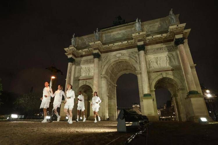 I tedofori con la fiaccola sotto l'Arco di Trionfo - Afp