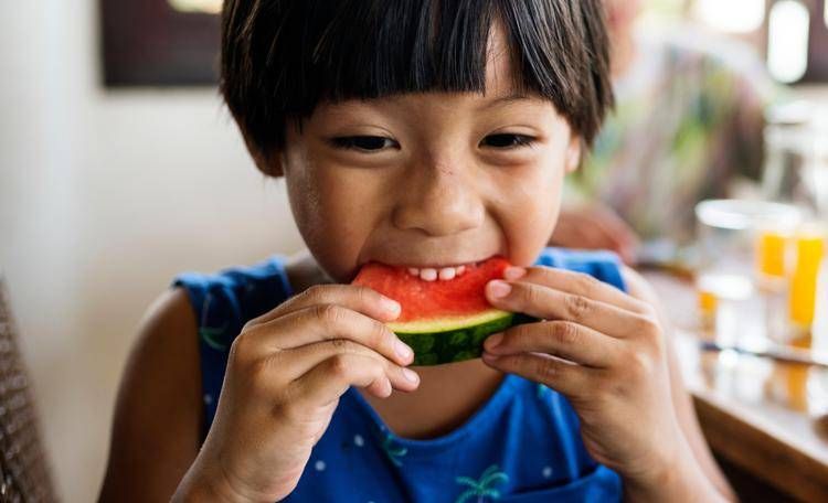 Un bambino addenta una fetta di cocomero - 

