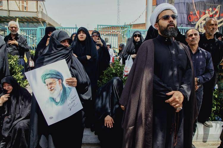Una donna piange mentre tiene un poster che mostra le immagini del leader supremo dell'Iran Ali Khamenei durante i funerali di comandanti militari iraniani e scienziati uccisi negli attacchi israeliani  - (Ipa)