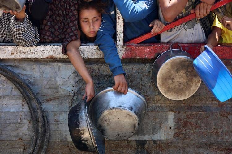 Bimbo con scodella vuota in attesa di cibo a Gaza - Afp
