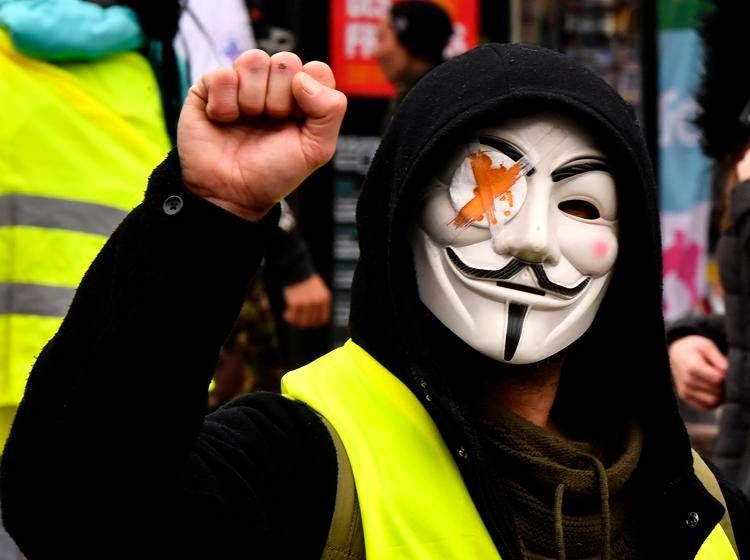 Un Gilet giallo versione Guy Fawkes durante la protesta dei 'Gilets Jaunes' tra il 2018 e il 2019 (Afp)