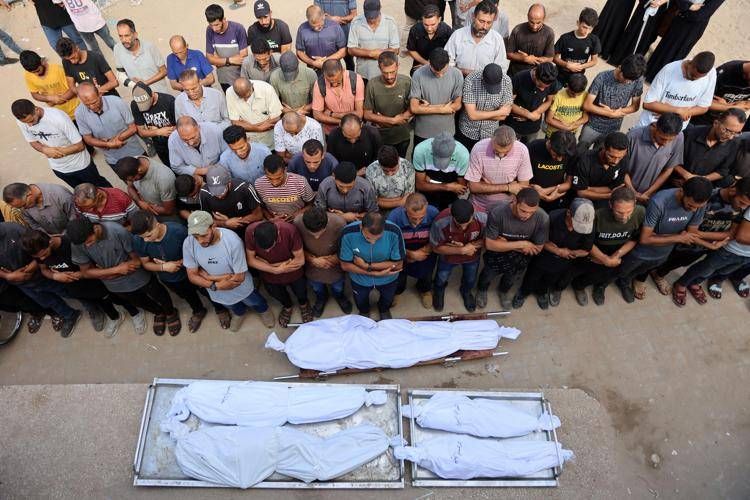 I palestinesi pregano davanti ai corpi avvolti in teli bianchi delle vittime degli attacchi israeliani sulla città di Gaza  - (Afp)