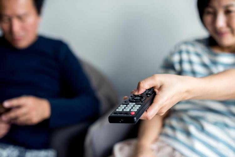 Una donna utilizza un telecomando per accendere la televisione - 

